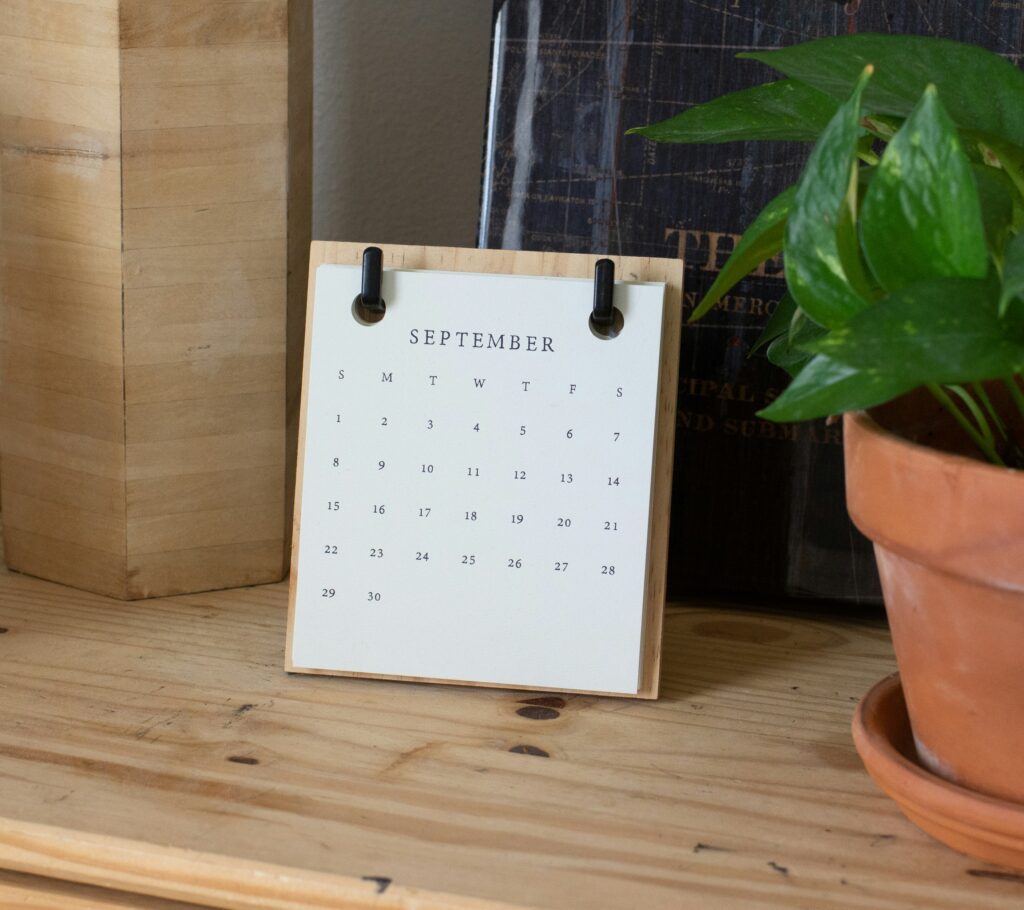 Desk calendar on a wooden table next to a potted plant